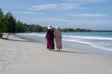 Two friends enjoy the beauty of Indonesia's tropical beaches. Two young women walk and talk on a beautiful tropical island beach
