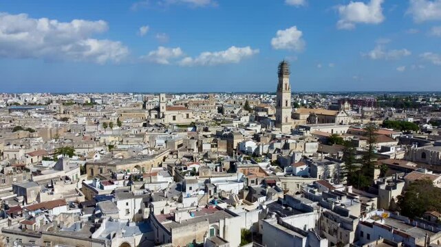 Aerial drone footage of Lecce, a baroque city in Apulia, southern Italy, showing historic architecture, churches, narrow streets, and rooftops under warm sunlight.