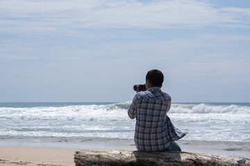 A man captures the beauty of Indonesia's tropical beaches on a sunny day. An aerial view shows a man photographing a tropical beach