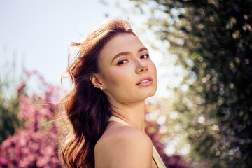 Young attractive woman with brunette hair outdoors on a sunny day, wearing a yellow outfit, enjoying nature