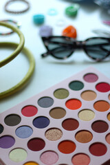 Green bag, various colorful jewelry, sunglasses, hair accessories and colorful make up on white...