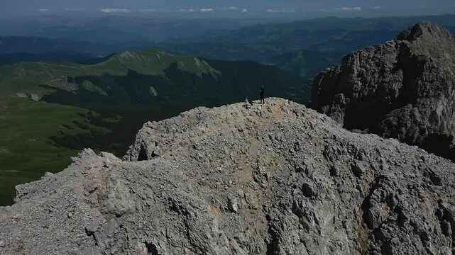 Aerial view of a tourist standing on the top of Mount Kucki Kom, the highest peak of the Komovi Mountains in Montenegro, and the surrounding picturesque panorama