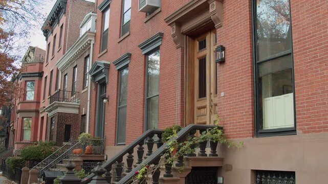 Charming brownstone facades with classic stoops and railings lining historic streets during autumn, capturing quintessential New York residential architecture