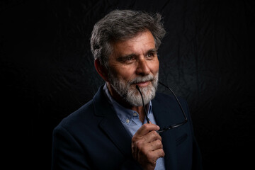 Portrait of handsome man in a studio on a dark background. Handsome man posing. Middle-aged good...