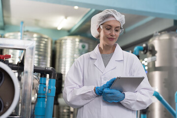 Drinking water manufacturers and production line. Water filter machine. Female worker inspecting...