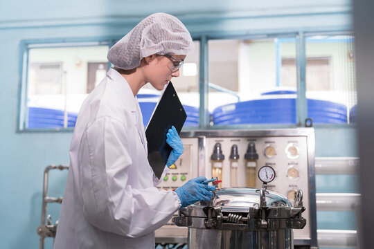 Drinking water manufacturers and production plant. Reverse osmosis water filter machine. Female worker inspecting quality of water filter machine in drinking water production plant