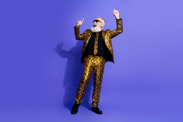 Confident senior man in a stylish gold suit dancing against a purple background, showcasing charisma, elegance