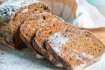 Freshly baked rye bread with sliced pieces displayed on a wooden surface in a cozy kitchen setting