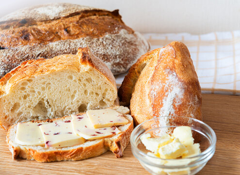 Freshly baked bread with butter and cheese on a wooden board in a cozy setting