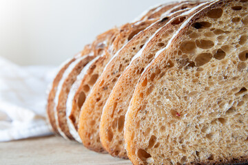 Freshly sliced artisanal bread arranged neatly on a wooden cutting board in a well-lit kitchen...