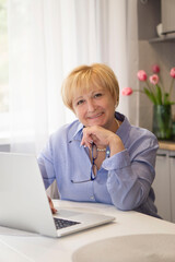 Senior Smiling Woman  working on laptop at home .  online  School teacher  concept .