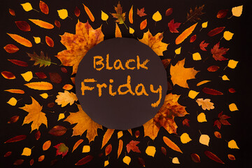 Autumn black background with yellow and red leaves and text black friday in the center. View from above. concept of black friday and discounts.
