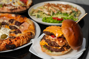 Table scene with a variety of delicious foods. Angled and perspective View over a dark wood background.