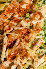 Penne pasta with spinach, cheese, chicken and salat on the side, close up