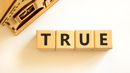 True symbol. Concept word True on beautiful wooden blocks. Beautiful wooden house. Beautiful white...