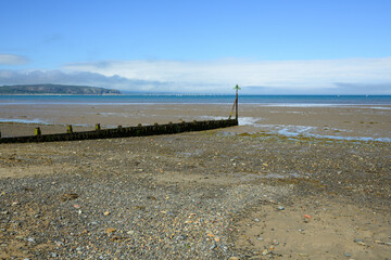 A beach with a wooden fence and a green post