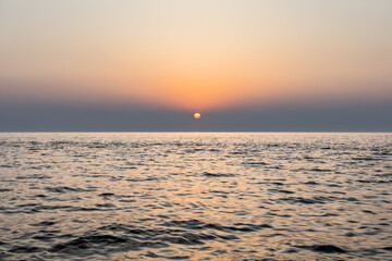 minimalist sea sunset with calm waves and orange hues. tranquil escape concept. sea water surface. clear sunset sky with copy