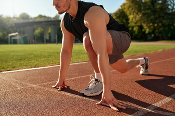 Athletic man in starting position on running track