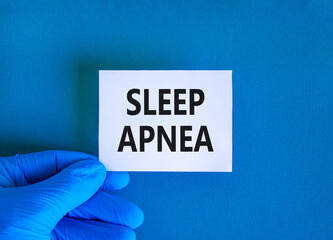 Sleep apnea symbol. Concept words Sleep apnea on beautiful white card. Doctor's hand in blue...