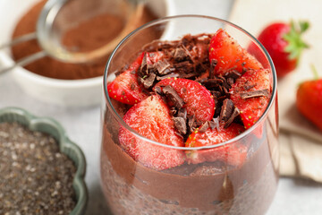 Delicious chocolate pudding with chia seeds and strawberries on table, closeup