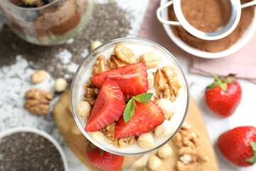 Delicious chocolate pudding with chia seeds, strawberries, yogurt and nuts in glass on white table,...