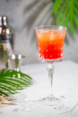 Colourful exotic Tequila Sunrise cocktail in a glass served with ice on gray background