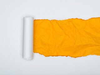 A piece of white paper is torn, revealing a crumpled bright orange background underneath.