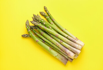 Fresh ripe raw asparagus on yellow background, top view