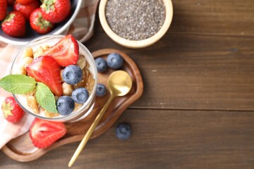 Delicious chocolate pudding with chia seeds, nuts and berries in glass on wooden table, flat lay. Space for text