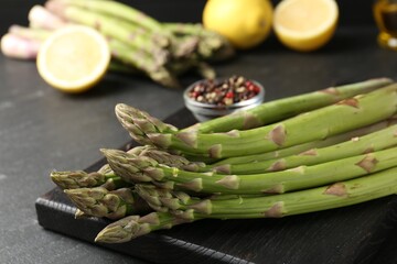 Fresh raw asparagus spears and spices on black table, closeup