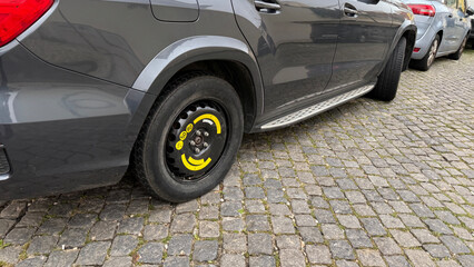 Gray car with neon yellow wheel detail rests on cobblestones, a secret urban explorers dream,...