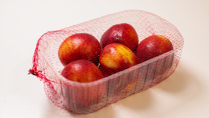 Summertime nectarines swathed in rustic mesh, evoking Augusts bounty, Midsummers Eve feasting, and tactile sensory indulgence