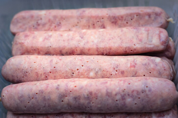 Raw Bavarian sausages prepared for grilling arranged on tray showing fresh meat texture close-up