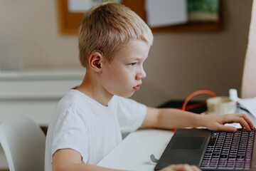 A boy with hearing aids enthusiastically plays computer games, showcasing inclusive play and...