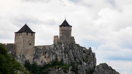 Ancient stone fortress crowns jagged cliffs under tumultuous skies, evoking medieval intrigue, fortress festivals, and history's hidden tales