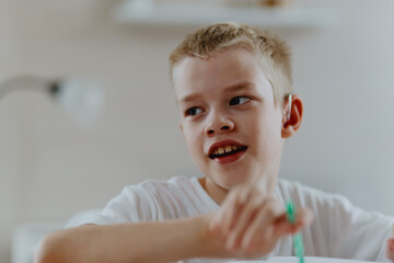 A boy with hearing aids focuses on homework, showcasing natural inclusive education. Authentic...