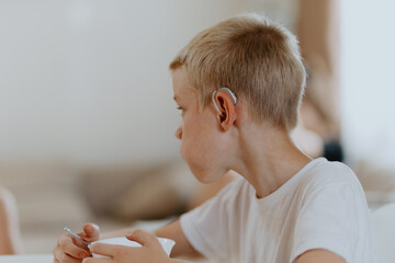 A boy with hearing aids enjoys a healthy breakfast, showcasing inclusive daily routines and...