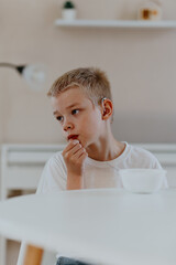 A boy with hearing aids enjoys a healthy breakfast, showcasing inclusive daily routines and...