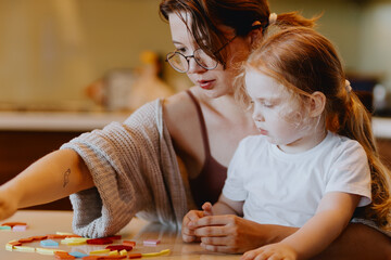 A sweet 3-year-old girl plays board games with her mom, sharing precious moments of love, learning...