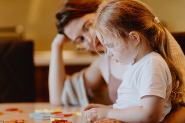 A sweet 3-year-old girl plays board games with her mom, sharing precious moments of love, learning...