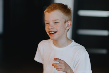 A blond boy with hearing aids gazes thoughtfully in a portrait celebrating inclusive beauty....