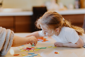 A sweet 3-year-old girl plays board games with her mom, sharing precious moments of love, learning and bonding. Perfect for family and early education content © looking2thesky