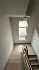Dimly lit stairwell embraces minimalist solitude, evoking serene contemplation, akin to Seclusion...