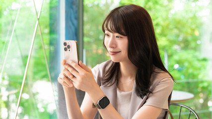 カフェでスマートフォンを使う笑顔の女性
