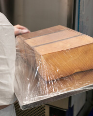A stack of wooden rectangles, shrouded in glistening plastic wrap, evokes an artisan's clandestine...