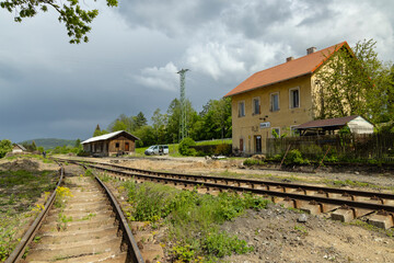 Old train station building with rusty rails and cloudy sky in Ustek, Czechia