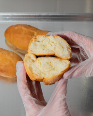 Gloved hands cradle freshly baked pandesal, evoking Filipino breakfast rituals and Pan de Sal Day...
