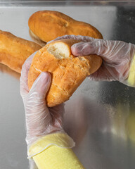 Plastic-gloved hands breaking crusty baguette, ideal for cozy baking rituals, World Baking Day,...