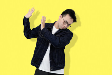 young asian man refusing or no pose in yellow isolated background