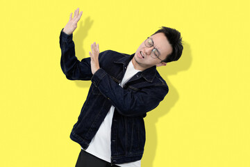 young asian man refusing or no pose in yellow isolated background